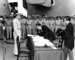 Foreign Minister Mamoru Shigemitsu signs for the Imperial Japanese Government. Standing by is General MacArthur's Chief of Staff, General Richard K. Sutherlin. Note General Richard Sutherlin at left.
