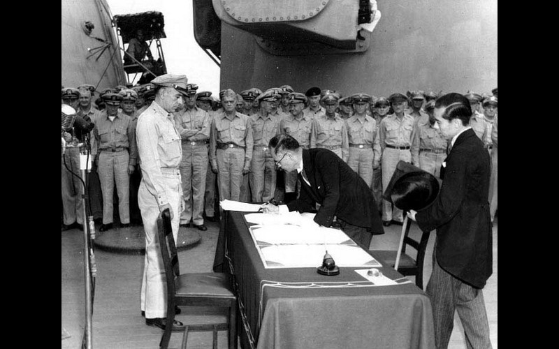 Foreign Minister Mamoru Shigemitsu signs for the Imperial Japanese Government. Standing by is General MacArthur's Chief of Staff, General Richard K. Sutherlin. Note General Richard Sutherlin at left.